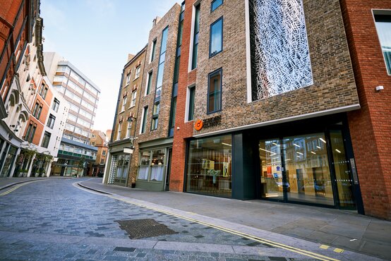 Multi-level brick building with large windows and glass entrance, Schön Klinik London on a narrow city street