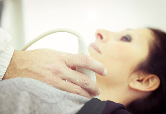 Doctor in a white coat performing an ultrasound examination on a woman's neck