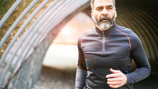 Man with beard jogging in sportswear through a tunnel in daylight