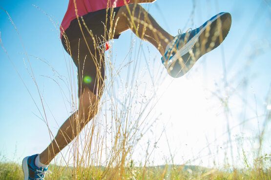 Close-up of feet running on a meadow in sunshine, focus on moving, pain-free ankle joint