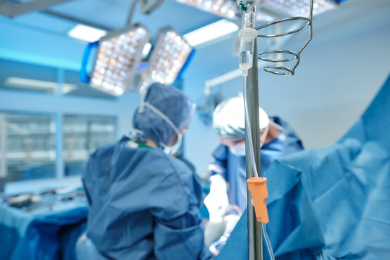 Medical team in sterile surgical clothing operates on patient with scoliosis in modern operating theatre