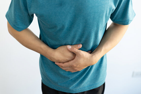 Person in blue T-shirt holding their stomach with both hands