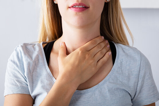 Woman touches her throat, suggesting thyroid discomfort or clinical neck symptoms