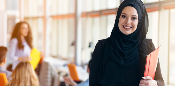 Young woman with black hijab holds red folder and smiles